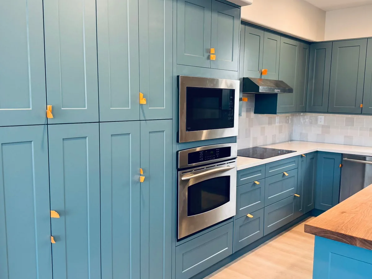 Blue painted kitchen cabinets with stainless wall ovens