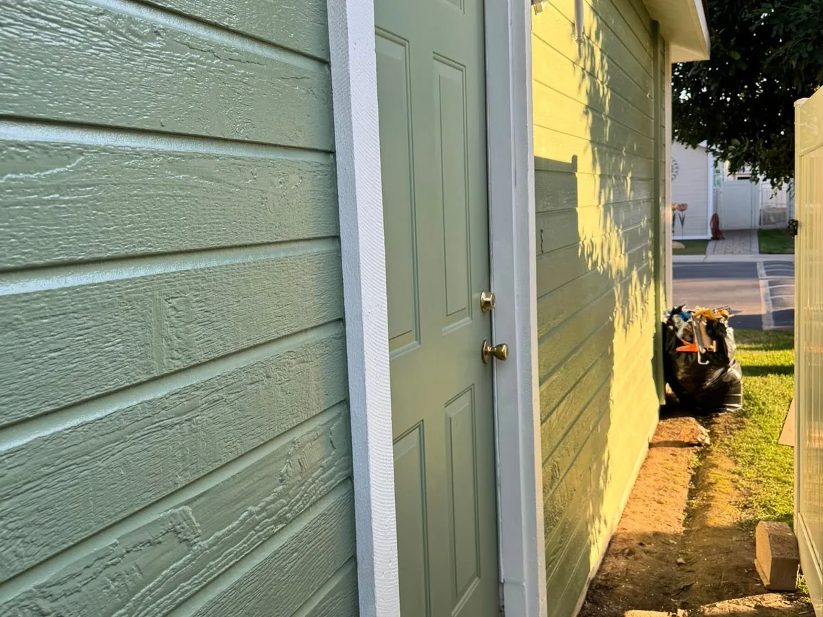 Sage green painted siding beside a white door frame