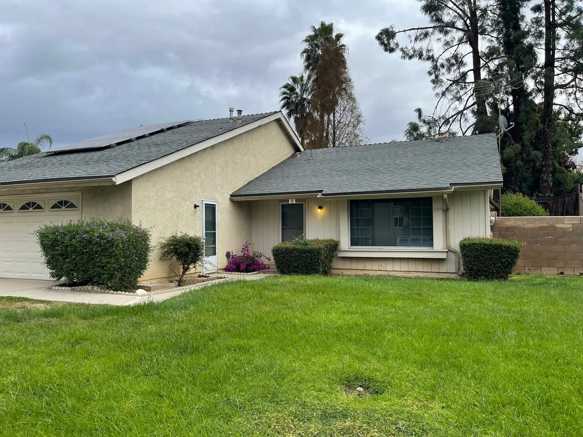 Painted tan stucco exterior with white window trim