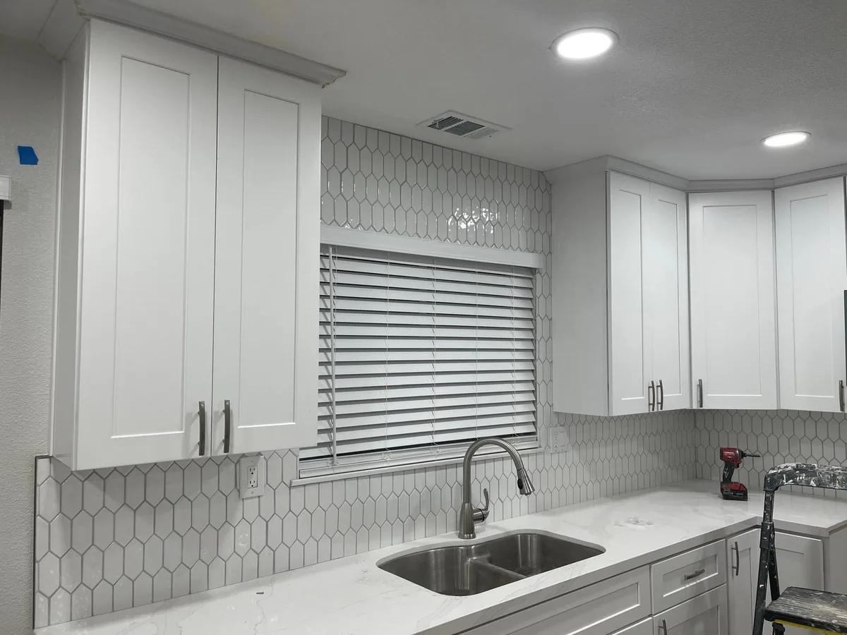 White kitchen cabinets painted above a tile backsplash